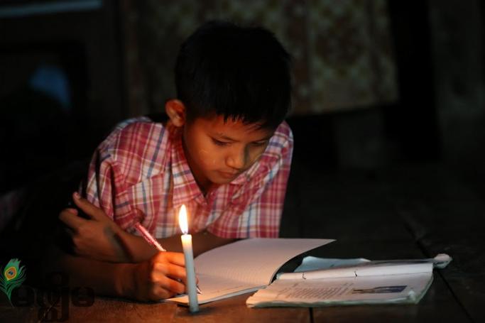 ဖယောင်းတိုင်မီးဖြင့် အိမ်စာလုပ်နေသည့် ကျောင်းသားတစ်ဦး (ဓာတ်ပုံ- ဟောင်ဆာ(ရာမည)/မဇ္ဈိမ)