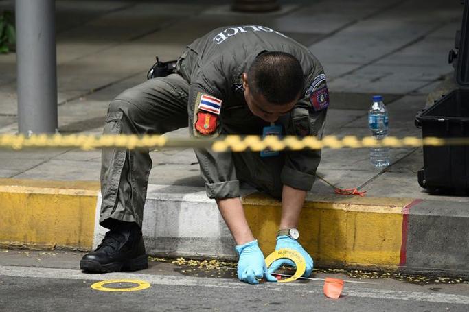 A policeman at the scene of one of the explosions (AFP Photo/Lillian SUWANRUMPHA )