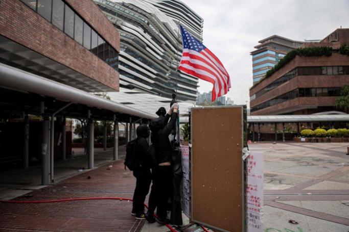 Protesters raise a US flag inside the Hong Kong Polytechnic University in the Hung Hom district of Hong Kong on November 20, 2019. AFP / NICOLAS ASFOURI