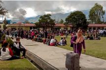 This picture taken on September 24, 2019 shows fleeing residents gathering at a field in Wamena, Papua province, as riots broke out in the restive region. - At least 32 people were killed and dozens injured in riots that paralysed Indonesia's restive Papua region, police said September 25, after one of the deadliest eruptions of violence in years. (Photo by VINA RUMBEWAS / AFP)